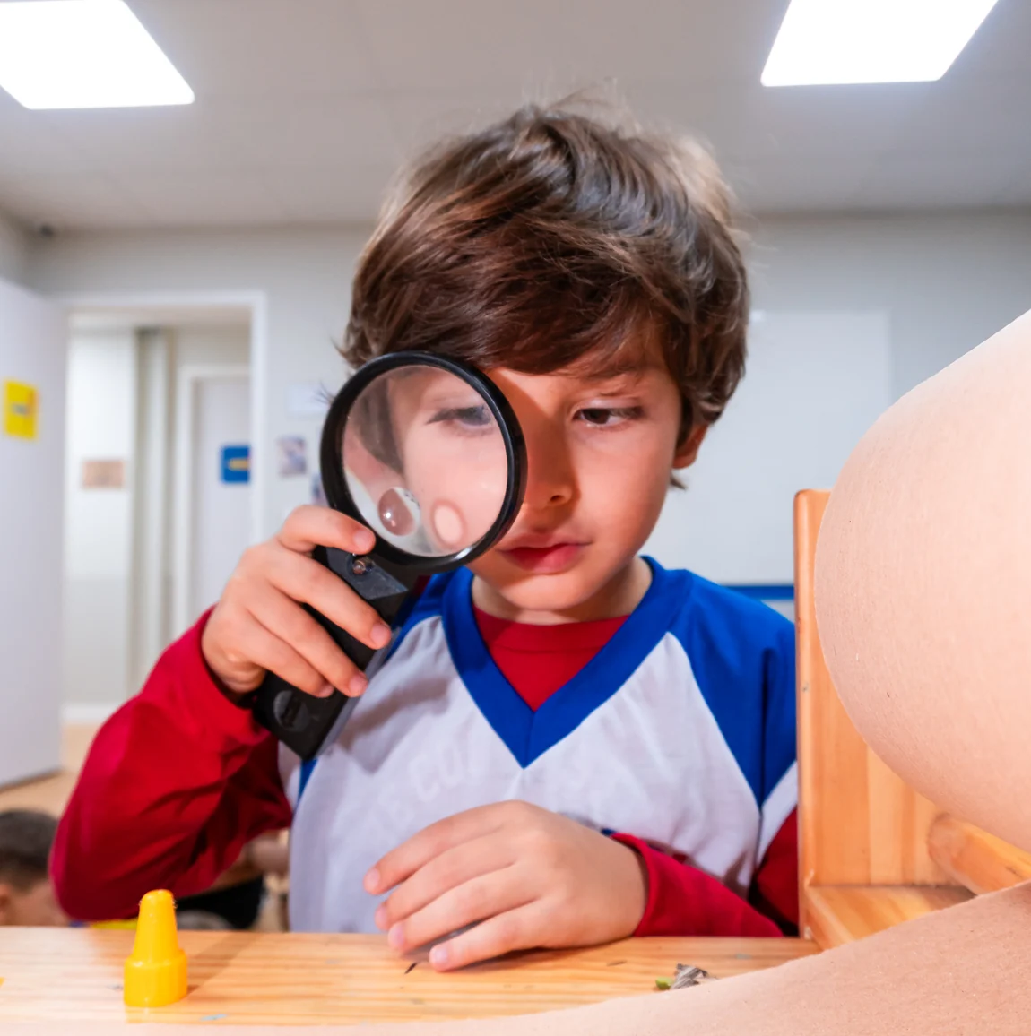 Aluno do Ensino Fundamental observando algo com uma lupa